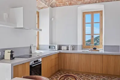 a kitchen with wooden cabinets and a window at Cargèse, appartement de charme surplombant le port in Cargèse