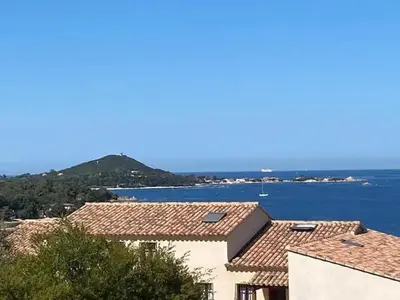 a view of the water and roofs of buildings at Appartement vue mer panoramique près de Porticcio in Pietrosella