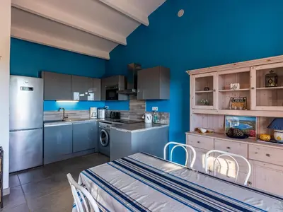 a kitchen with blue walls and a table and chairs at Holiday Home Pietralunga-1 by Interhome in Sotta