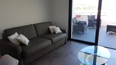 a living room with a couch and a glass table at Appartement neuf T2 centre de Porticcio in Porticcio