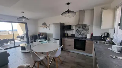 a kitchen with a table and chairs and a table and a kitchen with at Appartement neuf T2 centre de Porticcio in Porticcio