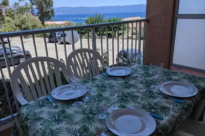 a table with plates and glasses on a balcony at Studio 4 pers terrasse vue mer in Ajaccio