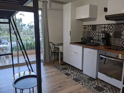 a kitchen with white cabinets and a table at Studio 4 pers terrasse vue mer in Ajaccio