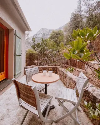 a table and chairs on a patio with a table at Auberge De La Foret Bonifatu in Calenzana