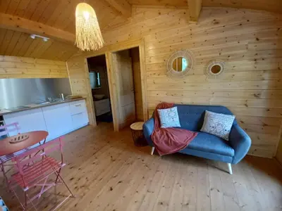 a living room with a blue couch and a kitchen at Auberge De La Foret Bonifatu in Calenzana