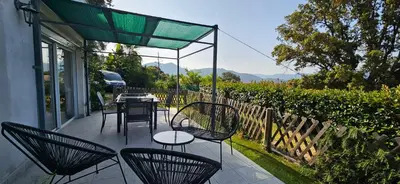 a patio with chairs and tables and a green canopy at Mini villa T2 climatisée, vue mer, cosy & moderne in Olmeto