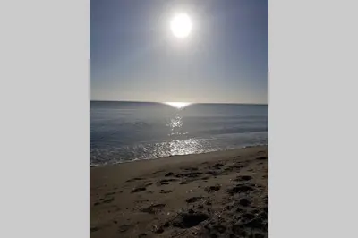 a view of a beach with the sun rising over the ocean at appartement tra mare e monti in Ghisonaccia