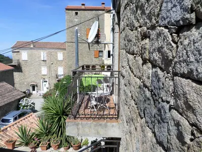 a balcony with a table and chairs on a wall at Appartement de charme entre mer et montagne in Sollacaro