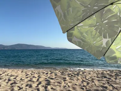 an umbrella on a sandy beach with the ocean at Appartement de charme entre mer et montagne in Sollacaro