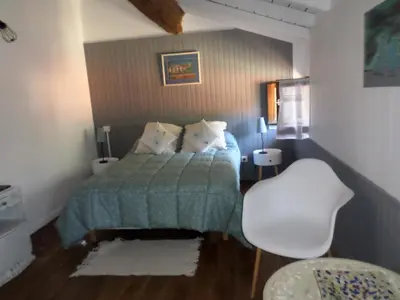 a bedroom with a bed and a white chair at Appartement de charme entre mer et montagne in Sollacaro