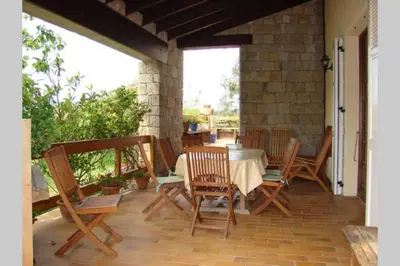a porch with a table and chairs on a patio at Maison de charme proche mer en Corse du Sud in Sollacaro