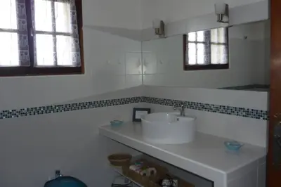 a white bathroom with a sink and two windows at Maison de charme proche mer en Corse du Sud in Sollacaro