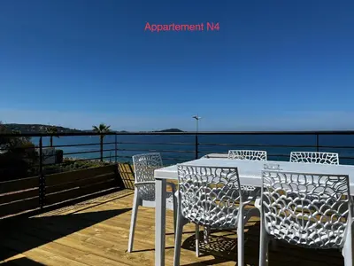 a table and chairs on a deck overlooking the water at Appartements résidence Harmonie vue mer in Porticcio