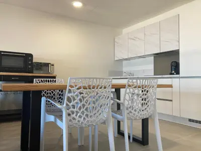a kitchen with a table with chairs and a microwave at Appartements résidence Harmonie vue mer in Porticcio