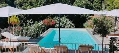 a swimming pool with a white umbrella and chairs and a pool at U Caseddu 