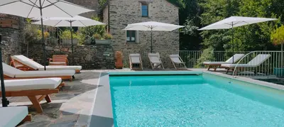 a swimming pool with chairs and umbrellas next to a building at Casetta in Ortiporio