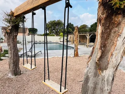 a swing in a tree next to a pool at Villa Santa Giulia in Porto-Vecchio