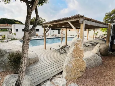 a wooden deck with chairs and a swimming pool at Villa Santa Giulia in Porto-Vecchio