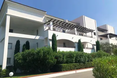 a large white building with bushes in front of it at Moriani-Plage : Résidence en bord de mer in San-Nicolao