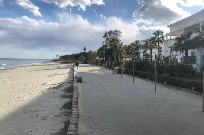 a person walking on a beach next to a building at Moriani-Plage : Résidence en bord de mer in San-Nicolao