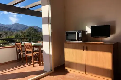 a kitchen with a microwave and a balcony with a television at Moriani-Plage : Résidence en bord de mer in San-Nicolao