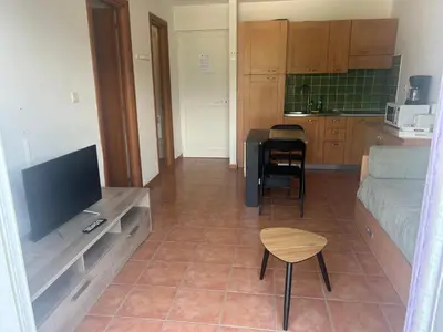 a living room with a couch and a tv and a kitchen at Moriani-Plage : Résidence en bord de mer in San-Nicolao