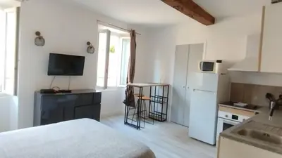 a small kitchen with a white refrigerator and a table at studio cosy centre ville in Ajaccio
