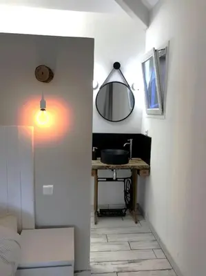 a room with a table and a mirror and a sink at Joli F1 en bordure d'Ajaccio in Ajaccio