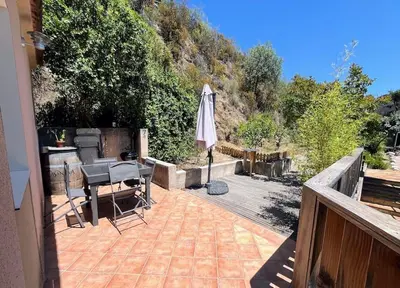 a patio with a table and an umbrella on a deck at Joli F1 en bordure d'Ajaccio in Ajaccio