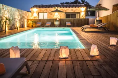 a swimming pool on a wooden deck with a house at Petra d'Oro Villa Palombaggia in Porto-Vecchio