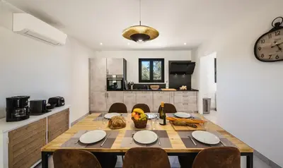 a dining room with a table and a kitchen at Petra d'Oro Villa Palombaggia in Porto-Vecchio