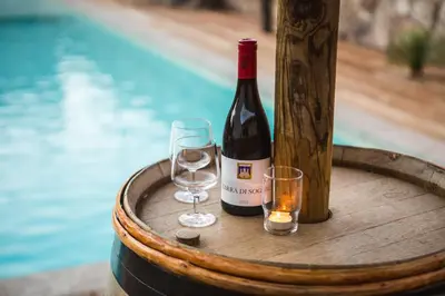 a bottle of wine and two glasses on a barrel at Petra d'Oro Villa Palombaggia in Porto-Vecchio