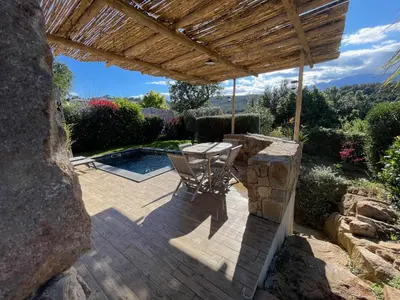 a wooden patio with a table and a wooden pergola at Villa Machja Solenzara in Sari Solenzara