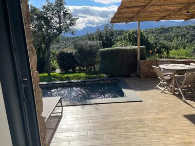 a patio with a pool and a table and an umbrella at Villa Machja Solenzara in Sari Solenzara