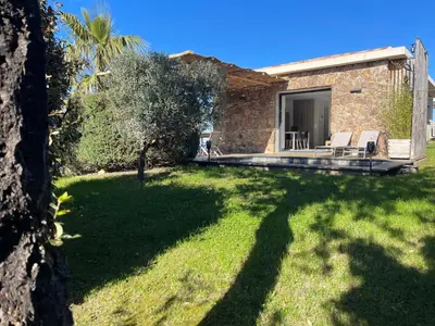 a house with a yard with two chairs and a patio at Villa Machja Solenzara in Sari Solenzara