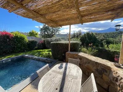 a patio with a table and chairs and a swimming pool at Villa Machja Solenzara in Sari Solenzara