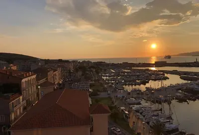 a sunset over a harbor with boats in the water at PORTO PIANO 2 pièces au coeur de la ville in Propriano