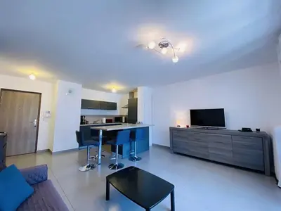 a large living room with a table and a kitchen at PORTO PIANO 2 pièces au coeur de la ville in Propriano