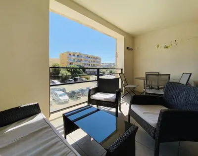 a balcony with chairs and a table and a large window at PORTO PIANO 2 pièces au coeur de la ville in Propriano