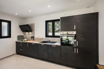 a kitchen with black cabinets and a sink at Résidence Petra d'Oro - Villa Rondinara in Porto-Vecchio