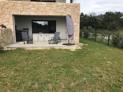 a patio with two chairs and an umbrella at Résidence de Tourisme 5* Porto Vecchio in Porto-Vecchio