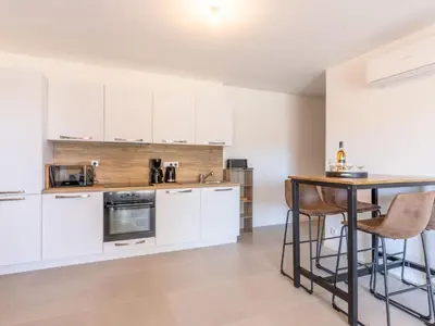 a kitchen with white cabinets and a table at Apartment St Joseph-1 by Interhome in Porto-Vecchio