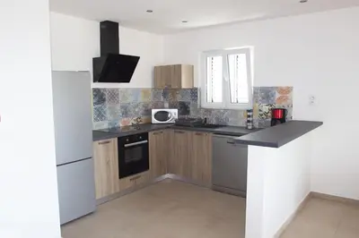 a kitchen with wooden cabinets and a white refrigerator at A SUARA LINDA in Ghisonaccia