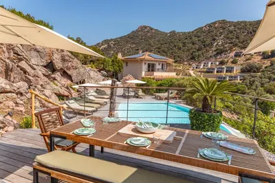 a patio with a table and chairs and a pool at Villa Elsa Di Palombaggia in Porto-Vecchio