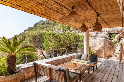 a patio with a table and chairs on a deck at Villa Elsa Di Palombaggia in Porto-Vecchio