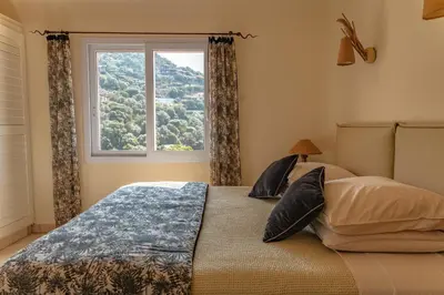 a bedroom with a bed with a large window at Villa Elsa Di Palombaggia in Porto-Vecchio