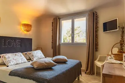 a bedroom with a bed with pillows and a window at Villa Elsa Di Palombaggia in Porto-Vecchio