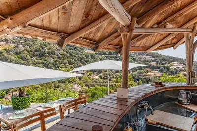 a wooden table with chairs and umbrellas on a balcony at Villa Elsa Di Palombaggia in Porto-Vecchio