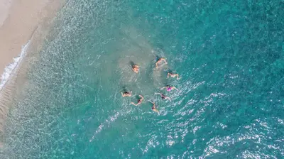 a group of people swimming in the ocean on a beach at Camping Merendella in San-Nicolao