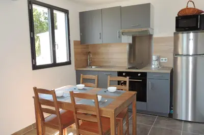 a kitchen with a table and chairs and a refrigerator at L'Ortu Di Pisettu -1 in Conca